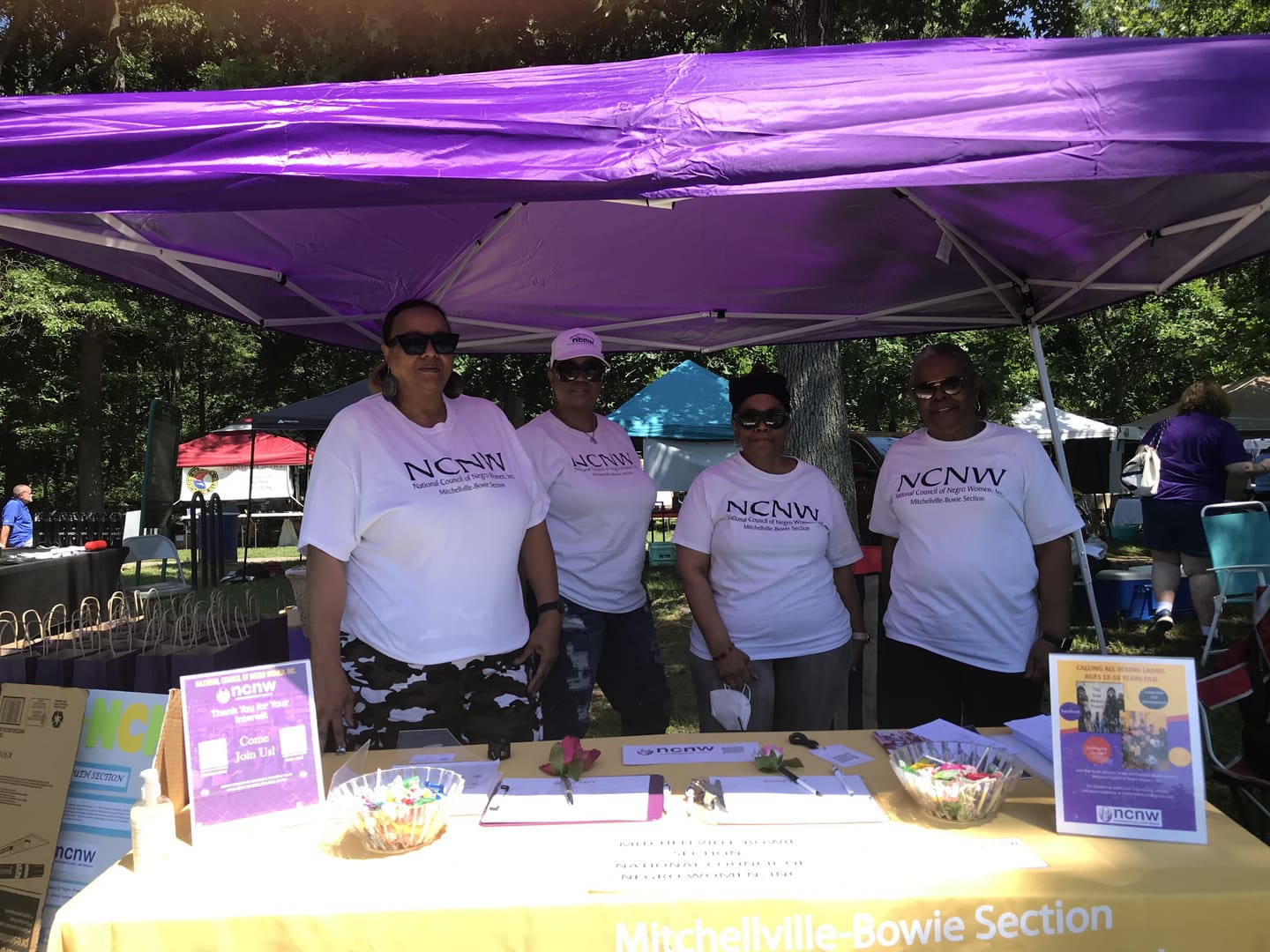 A group of people standing under a purple tent.