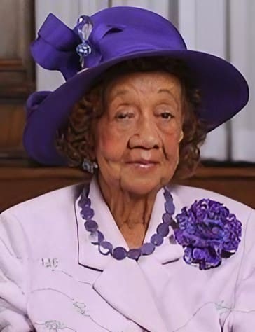 A woman in a purple hat and necklace.