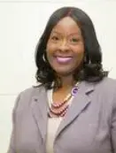 A woman in a gray jacket and purple necklace.