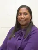 A woman in purple shirt and black pants.