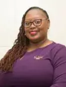 A woman with long hair wearing glasses and purple shirt.