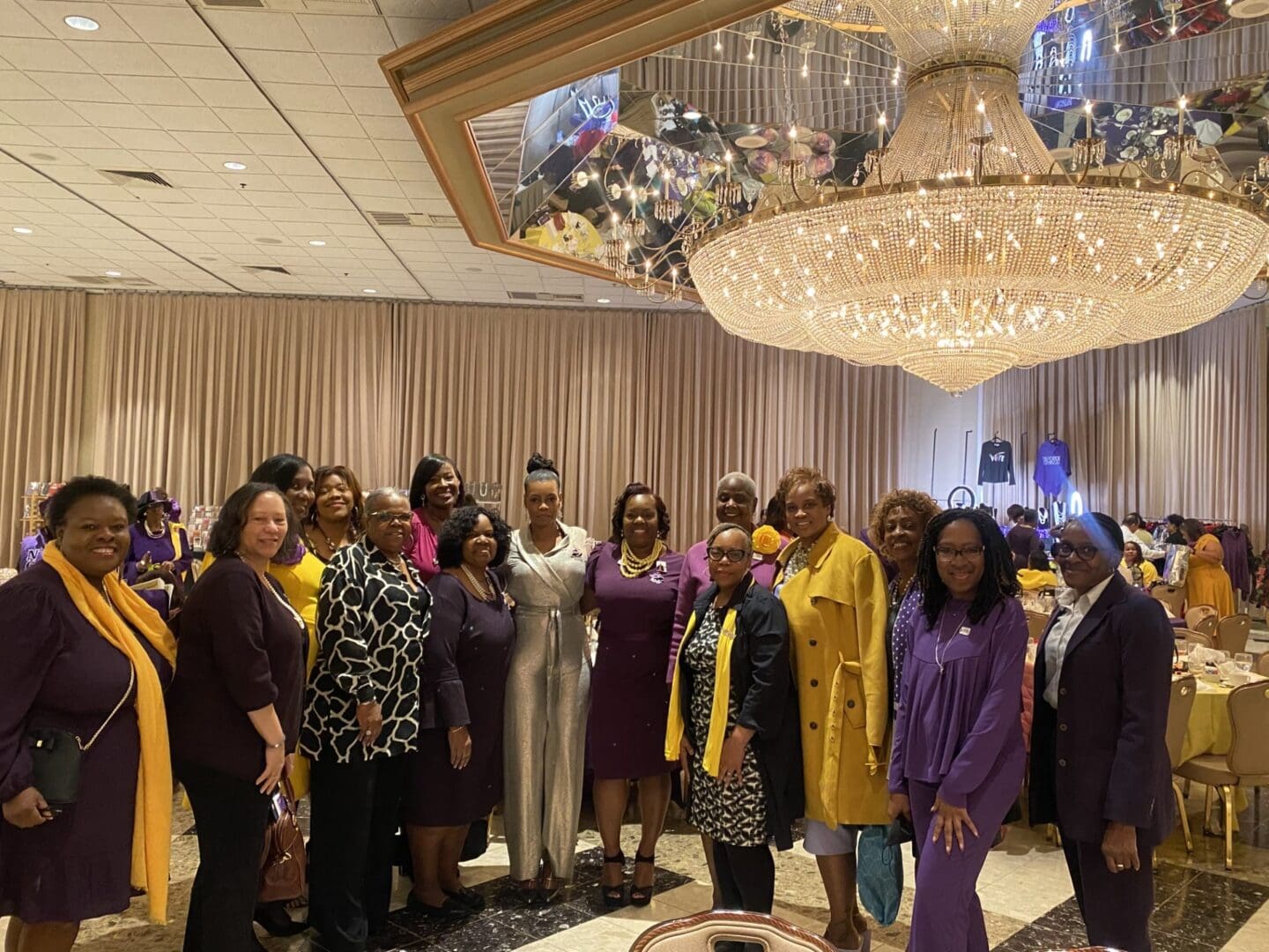 A group of women standing in front of a chandelier.