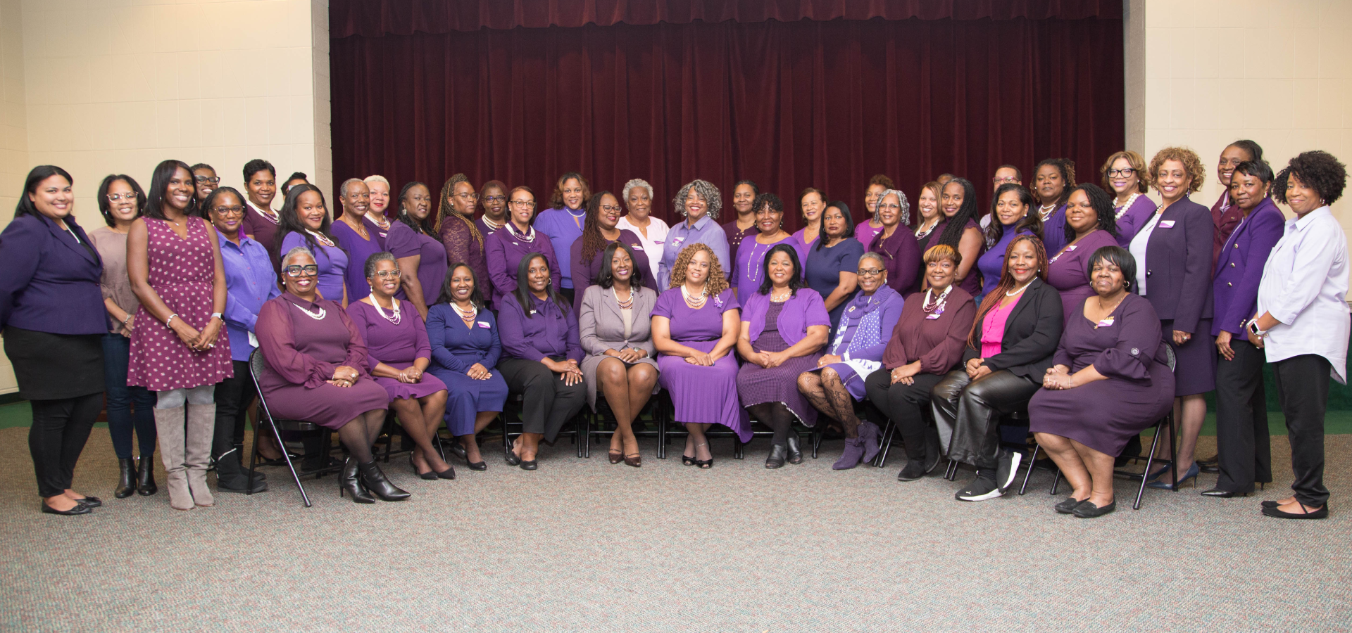 A group of women in purple outfits sitting on the ground.