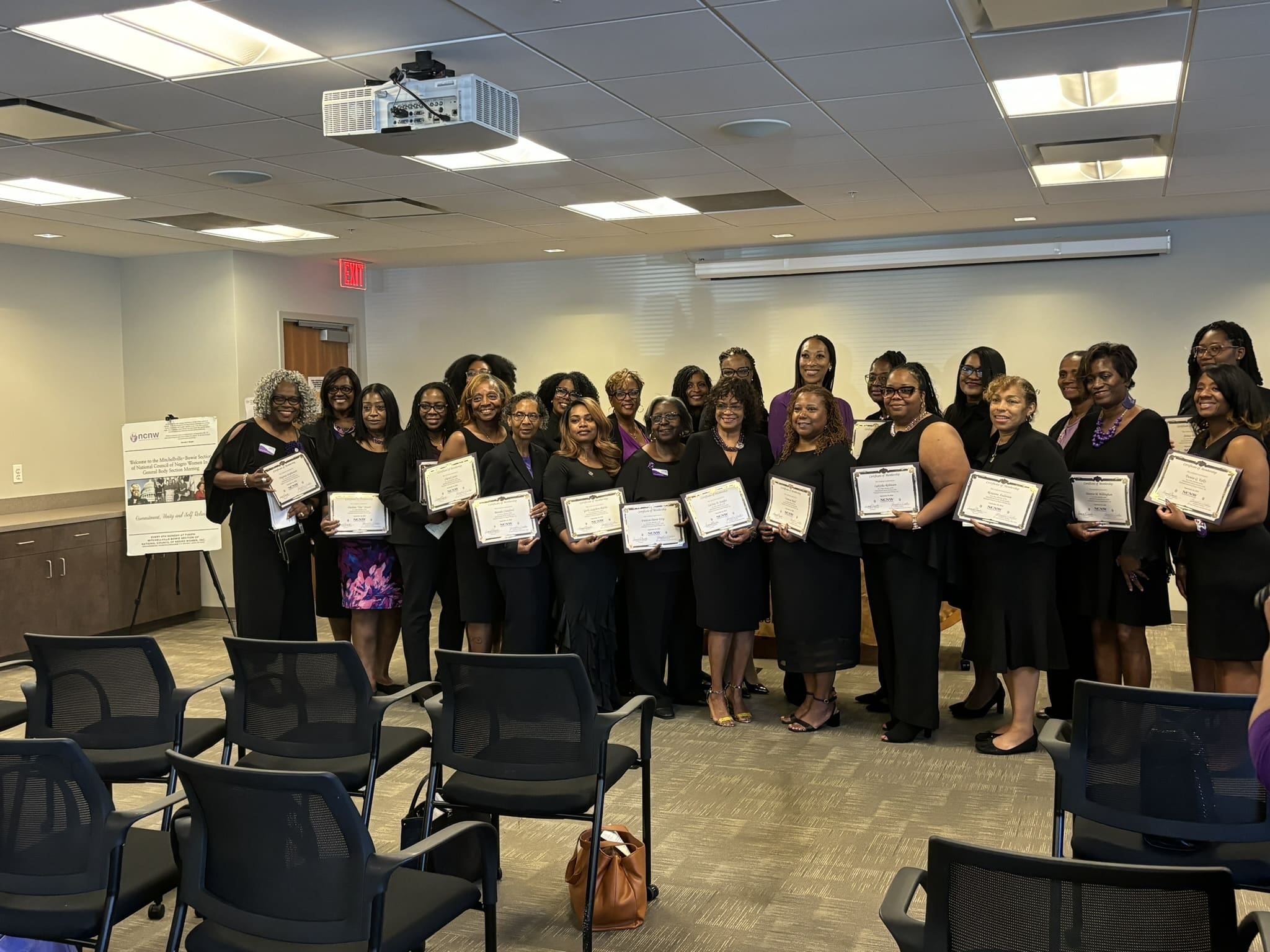 A group of women in black dresses holding certificates.