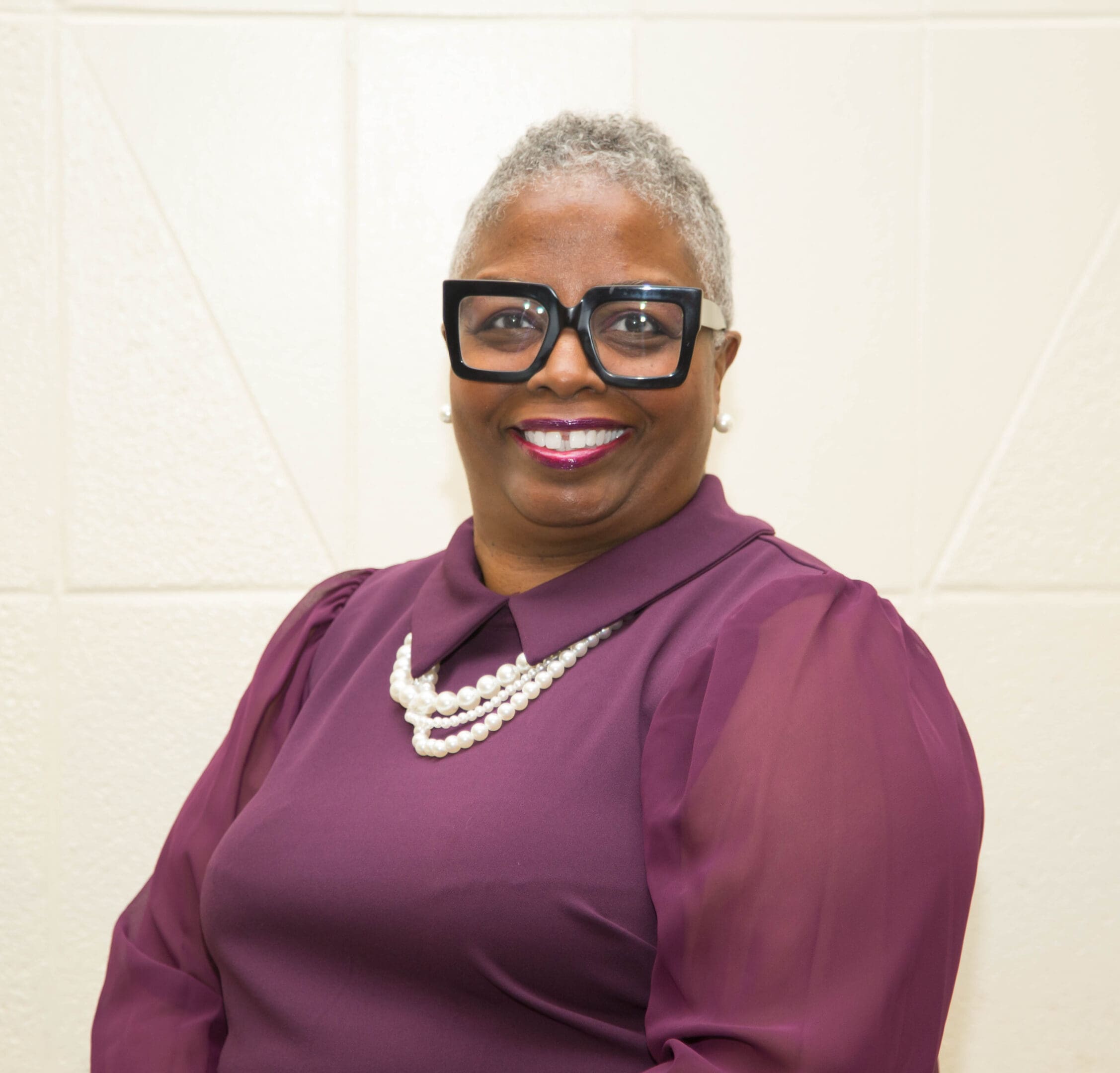 A woman in purple shirt and black glasses.